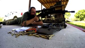 Shooter in prone position logging DOPE with box of match-grade ammunition and spent shells during Tactical U Precision Scoped Rifle Course.