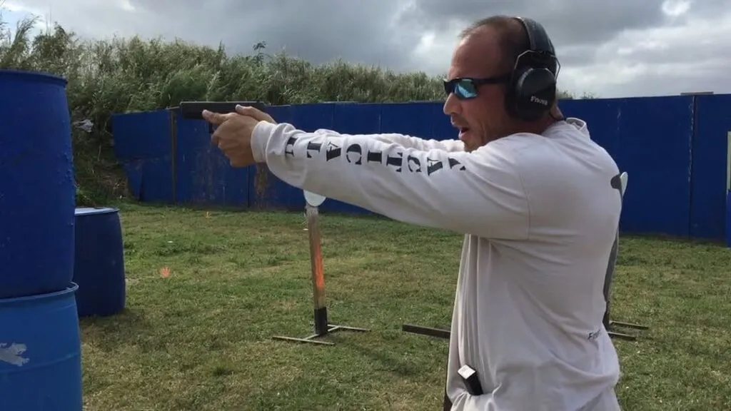 Student in a Tactical U shirt firing a pistol on the outdoor range
