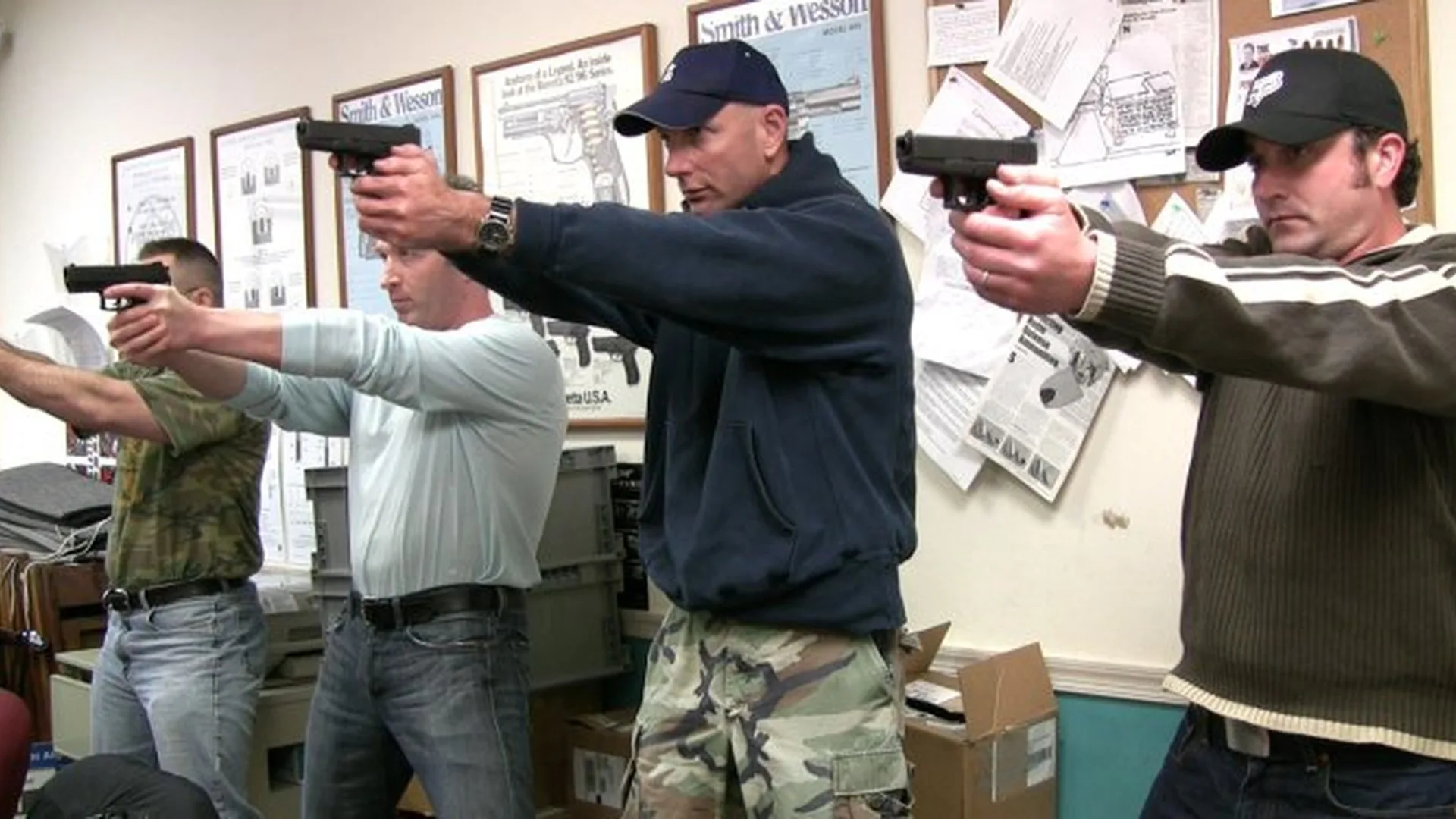 Beginner firearm safety students practicing safe handgun handling in a classroom setting at Tactical U.