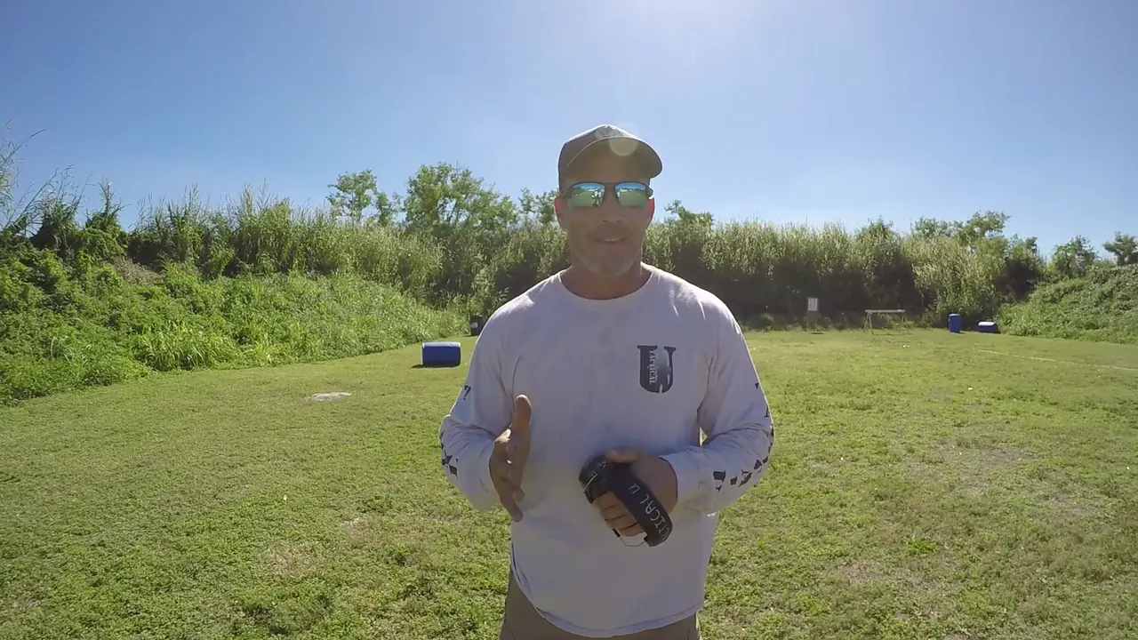 Instructor holding a belt holster and magazine pouch while explaining what to bring
