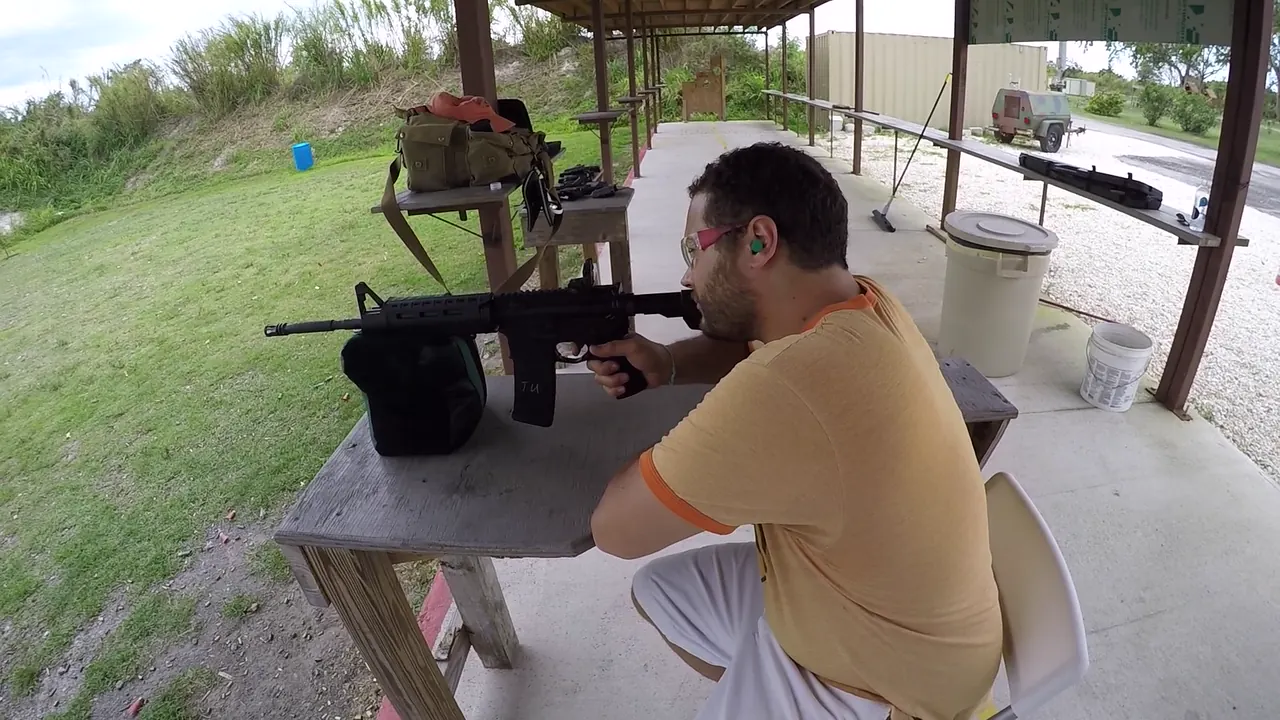 Student at a covered shooting bench with a rifle rest, range bag and gear