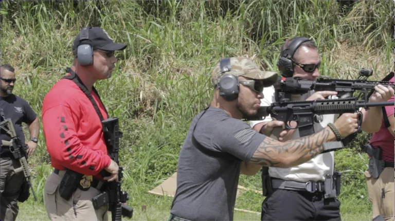 Stephen L. Cohen in a red shirt supervising rifle students on an outdoor range