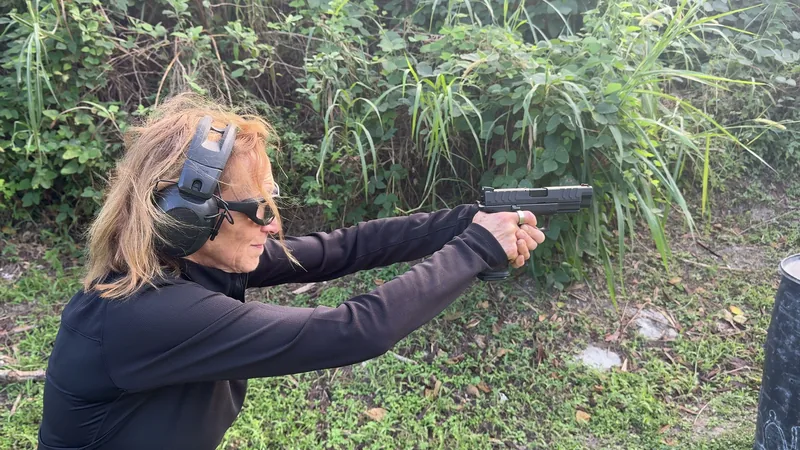 Student in black aiming a pistol at a target