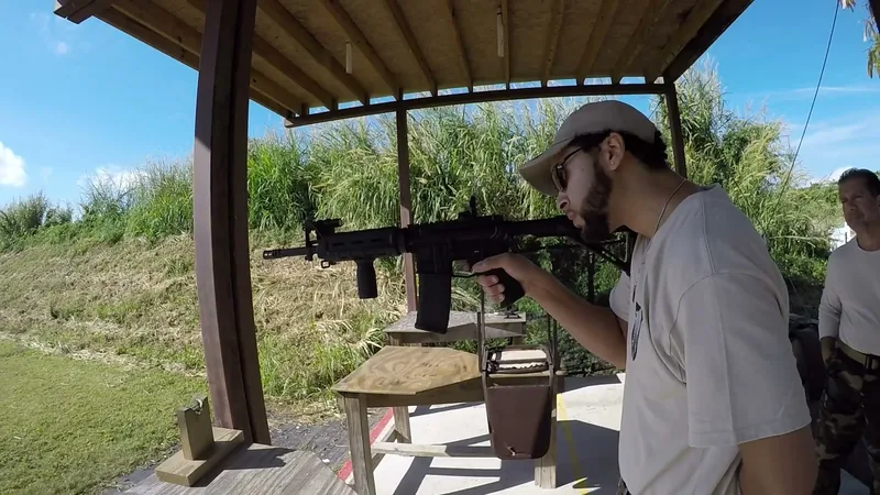 Student firing an AR-style rifle from the bench under the range pavilion