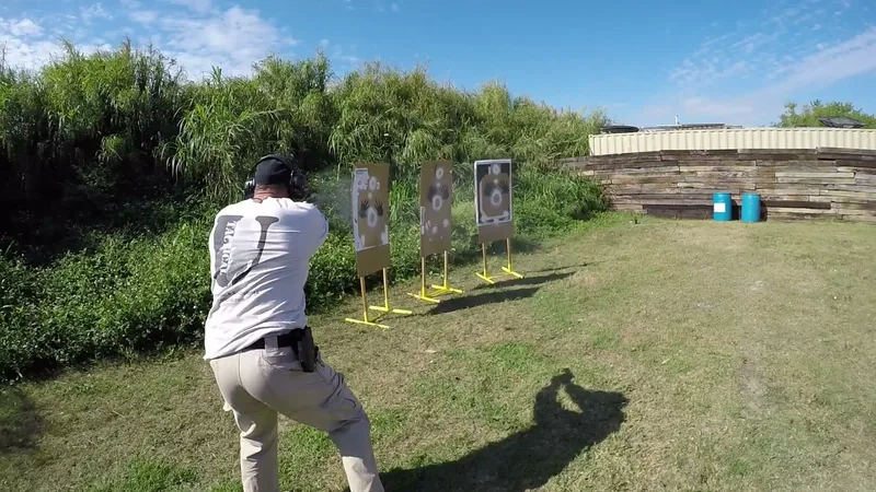 Student in a Tactical U shirt firing a pistol at a row of targets