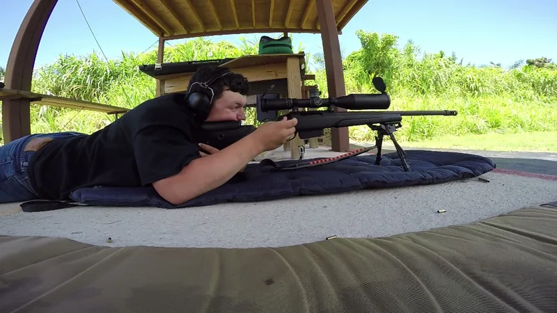 Student prone behind a scoped precision rifle on a shooting mat