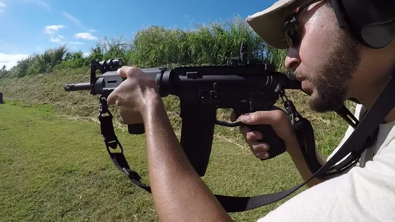 Close view of a student shouldering an AR-style rifle with a sling