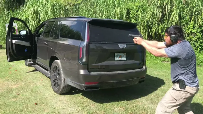 Student firing a pistol beside an SUV during vehicle tactics