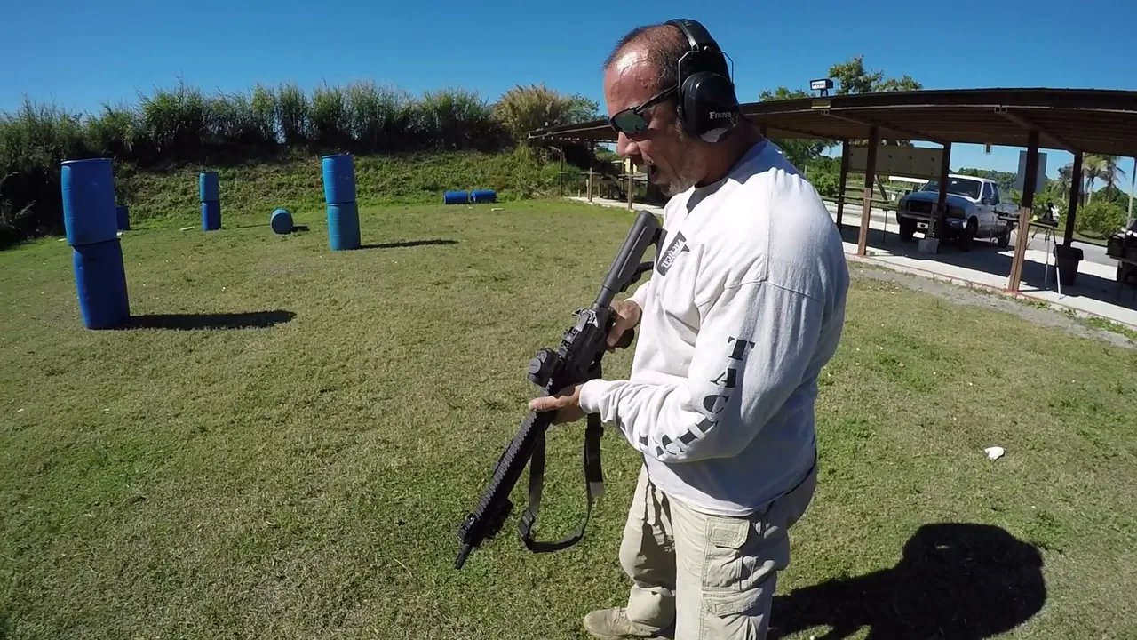 Tactical U instructor demonstrating one-hand rifle manipulation on an outdoor range
