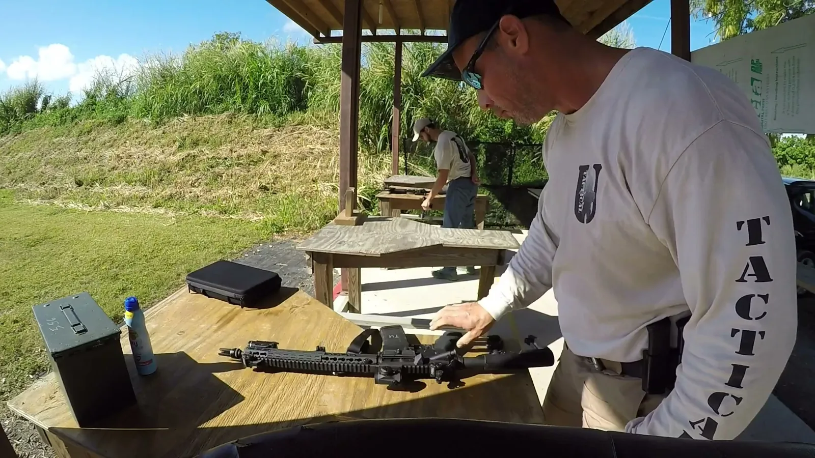 Tactical U instructor in a Tactical U shirt clearing a rifle malfunction at the shooting bench
