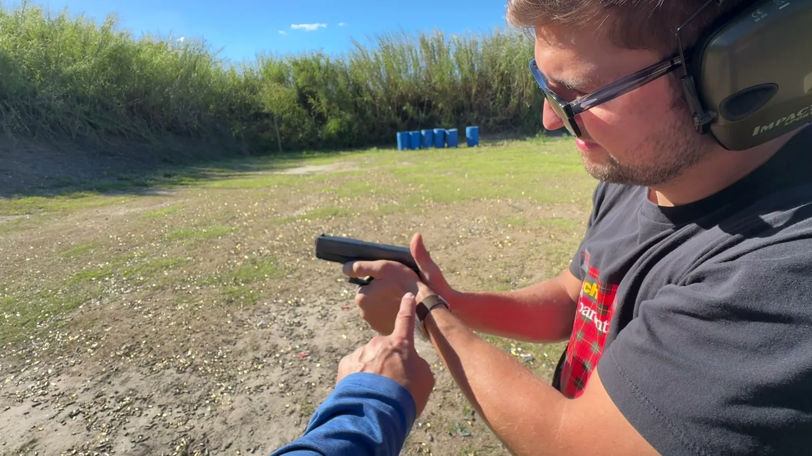 Tactical U instructor pointing to a student's pistol grip during a live-fire on an outdoor range