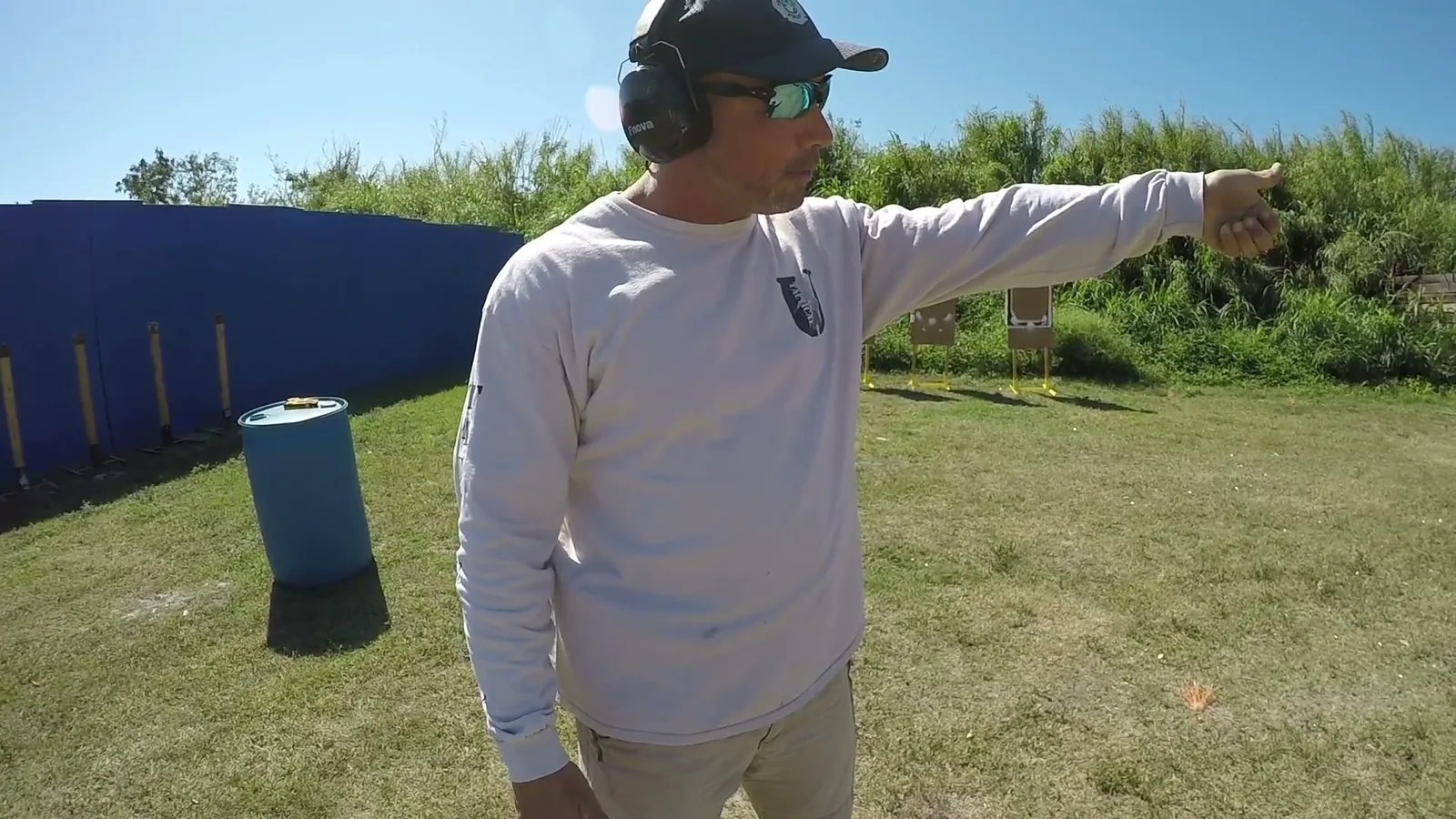 Tactical U instructor in ear protection pointing downrange while explaining a drill on an outdoor range