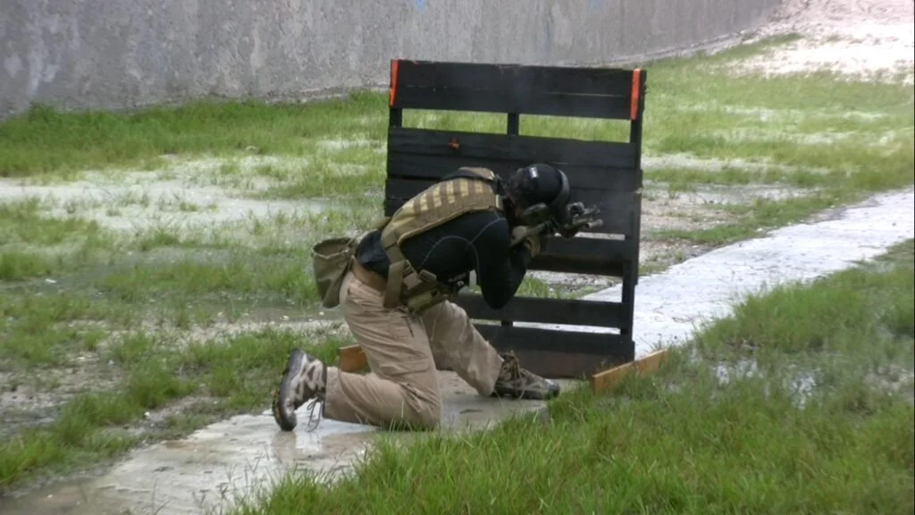 A rifle student positioned beside a training barrier on an outdoor range