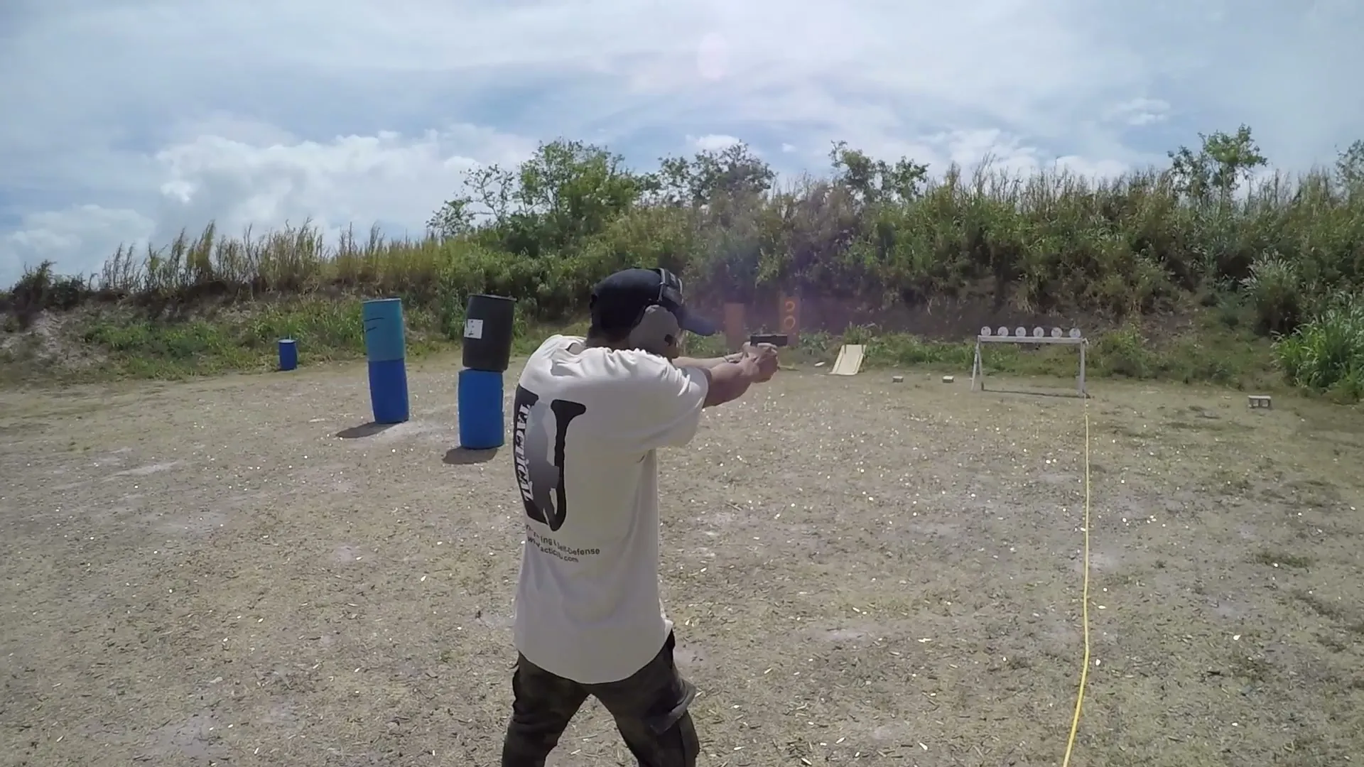 Tactical U student firing a handgun at steel plates on an outdoor South Florida range during live-fire training