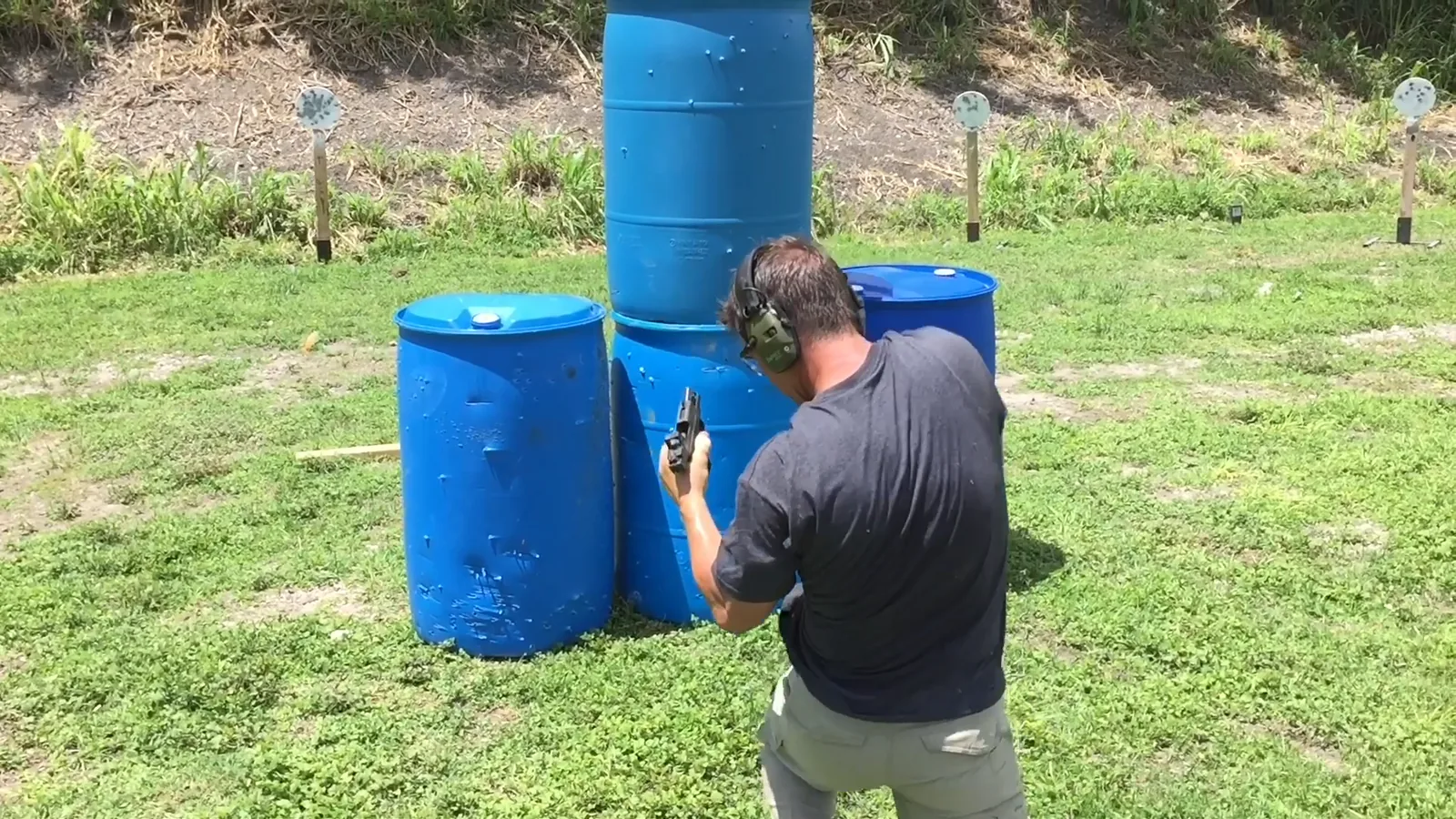 Student shooting around blue barrel cover with a weapon-mounted light during a daylight drill