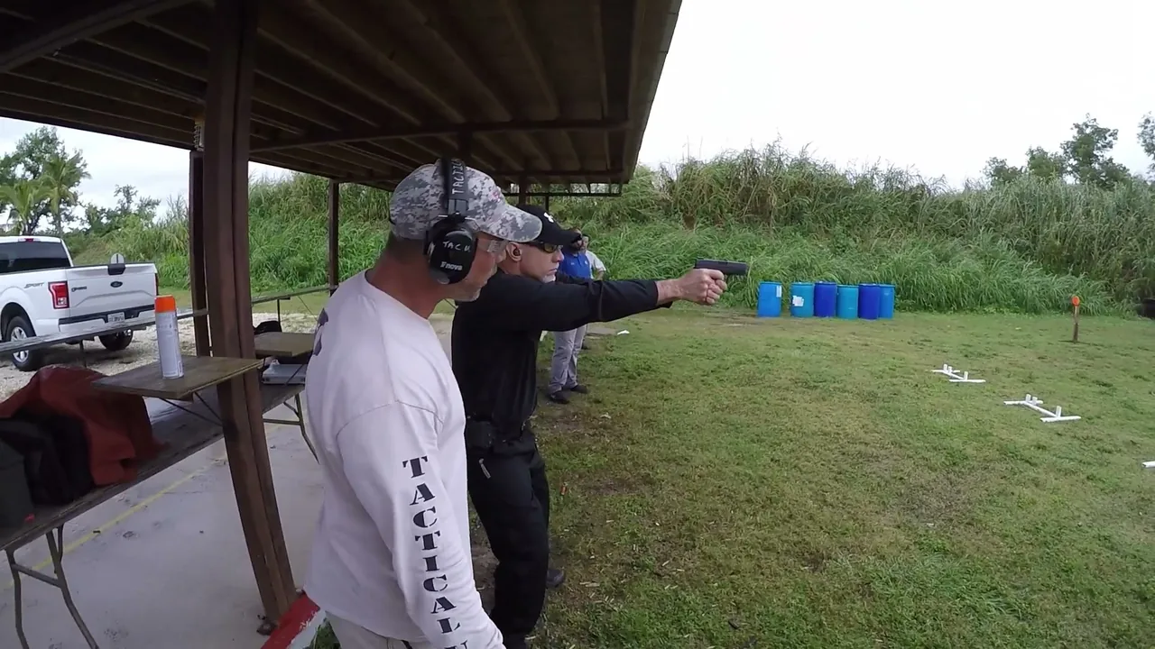 Tactical U instructor coaching a student firing a pistol at the covered firing line