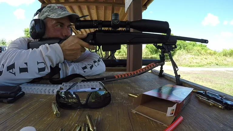 Stephen L. Cohen looking through a scoped rifle from a supported bench position