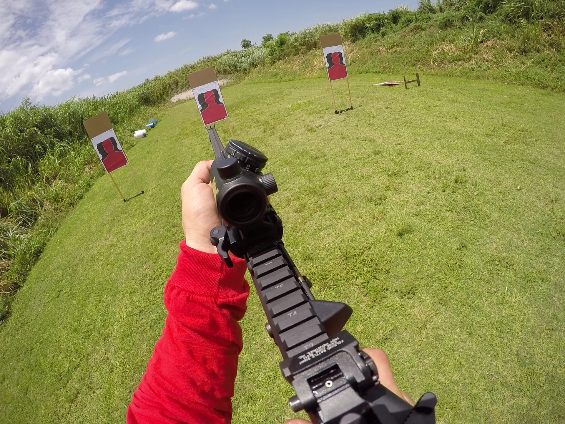 View over a Tactical U rifle and optic toward three targets on an outdoor range