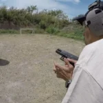 Tactical U handgun student with hearing protection handling a pistol on the range during a live-fire class